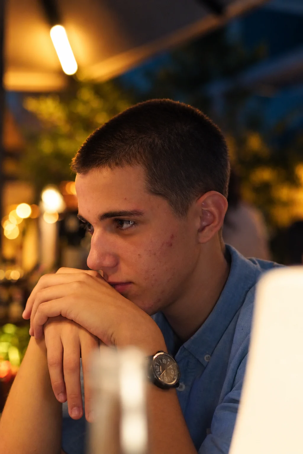 Un homme en chemise bleue, les mains jointes devant son visage, série flo.