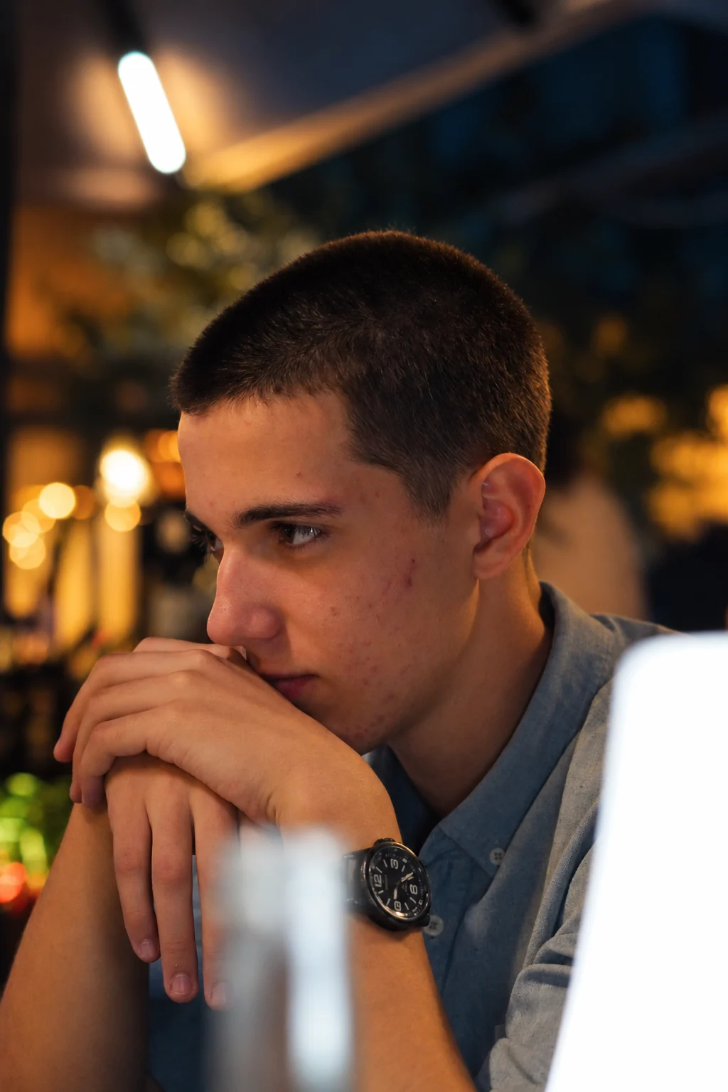Portrait vertical d’un homme en chemise bleue, les mains rapprochées, série flo.