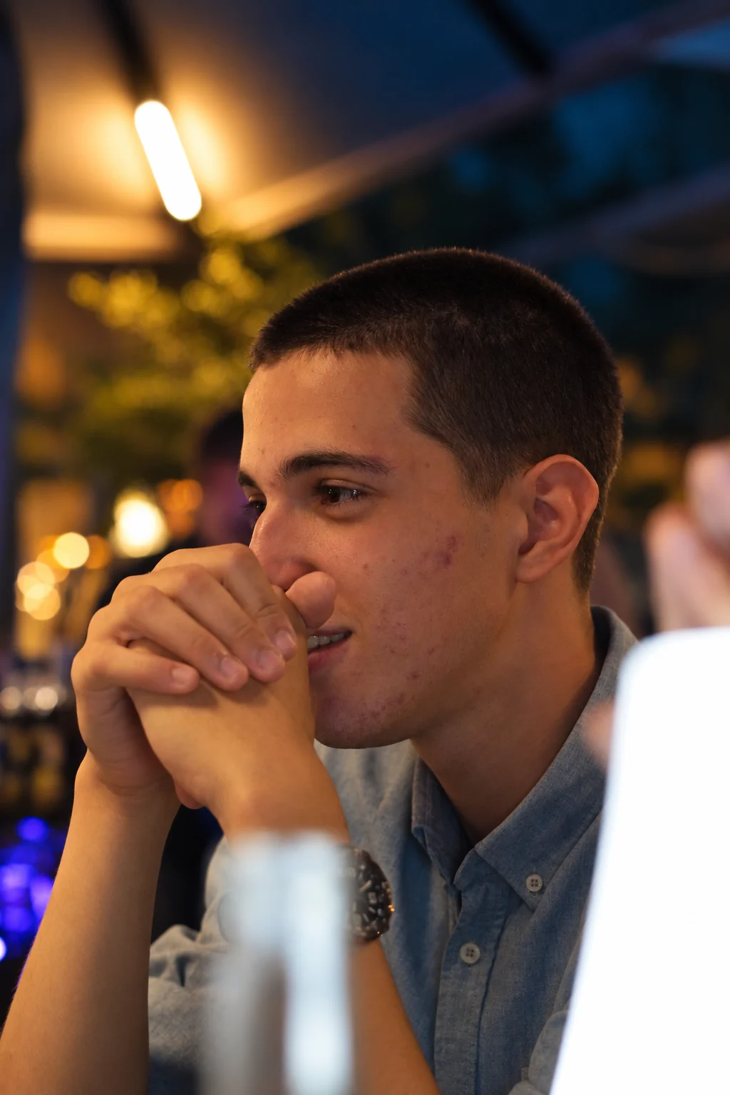 Un homme en chemise bleue, une main près de sa bouche, série flo.