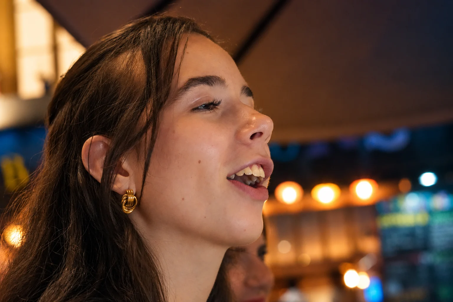 Portrait de profil d’une femme, la bouche ouverte, dans une lumière chaleureuse, série flo.