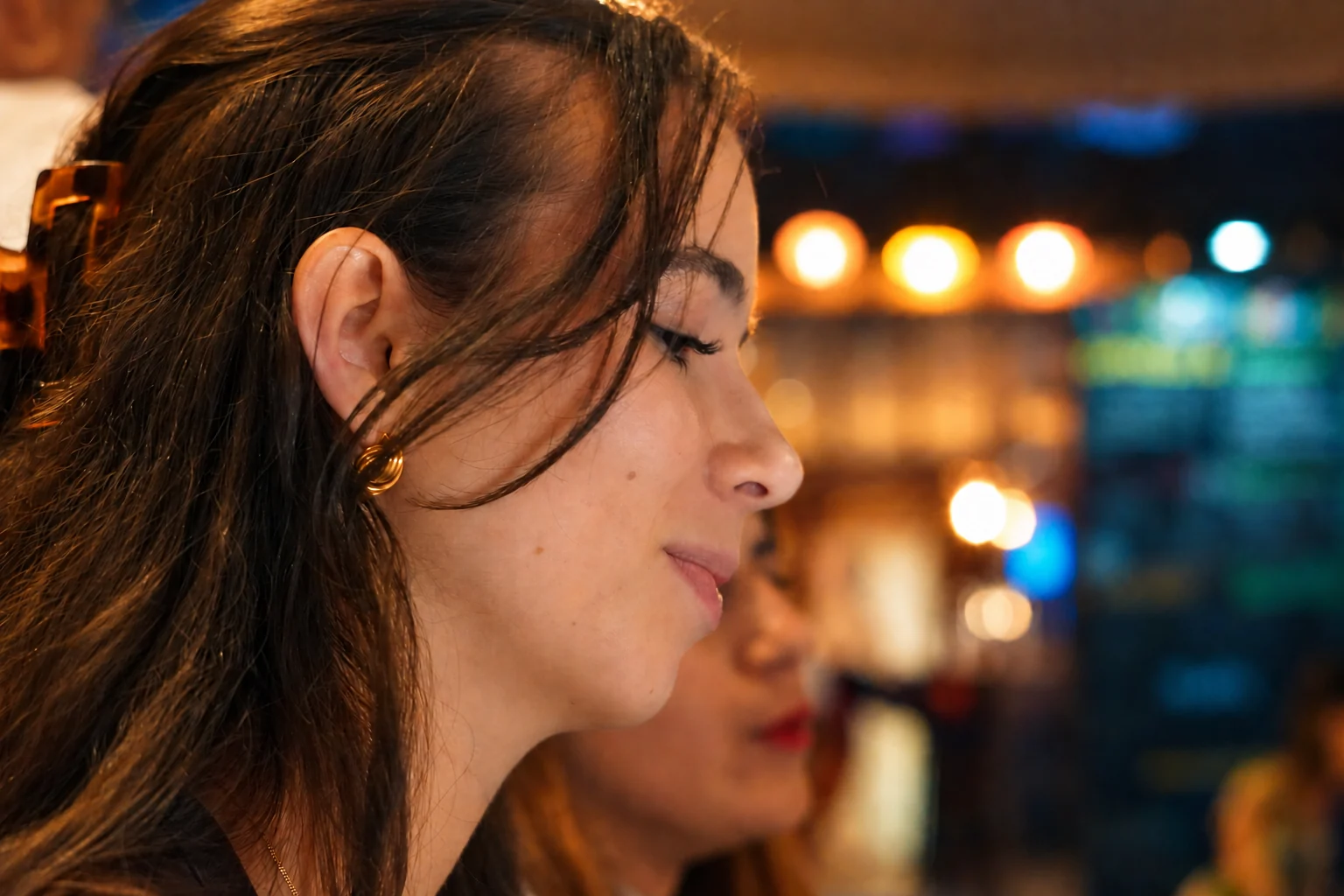 Une femme de profil ferme les yeux, avec des lumières chaudes en arrière-plan, série flo.