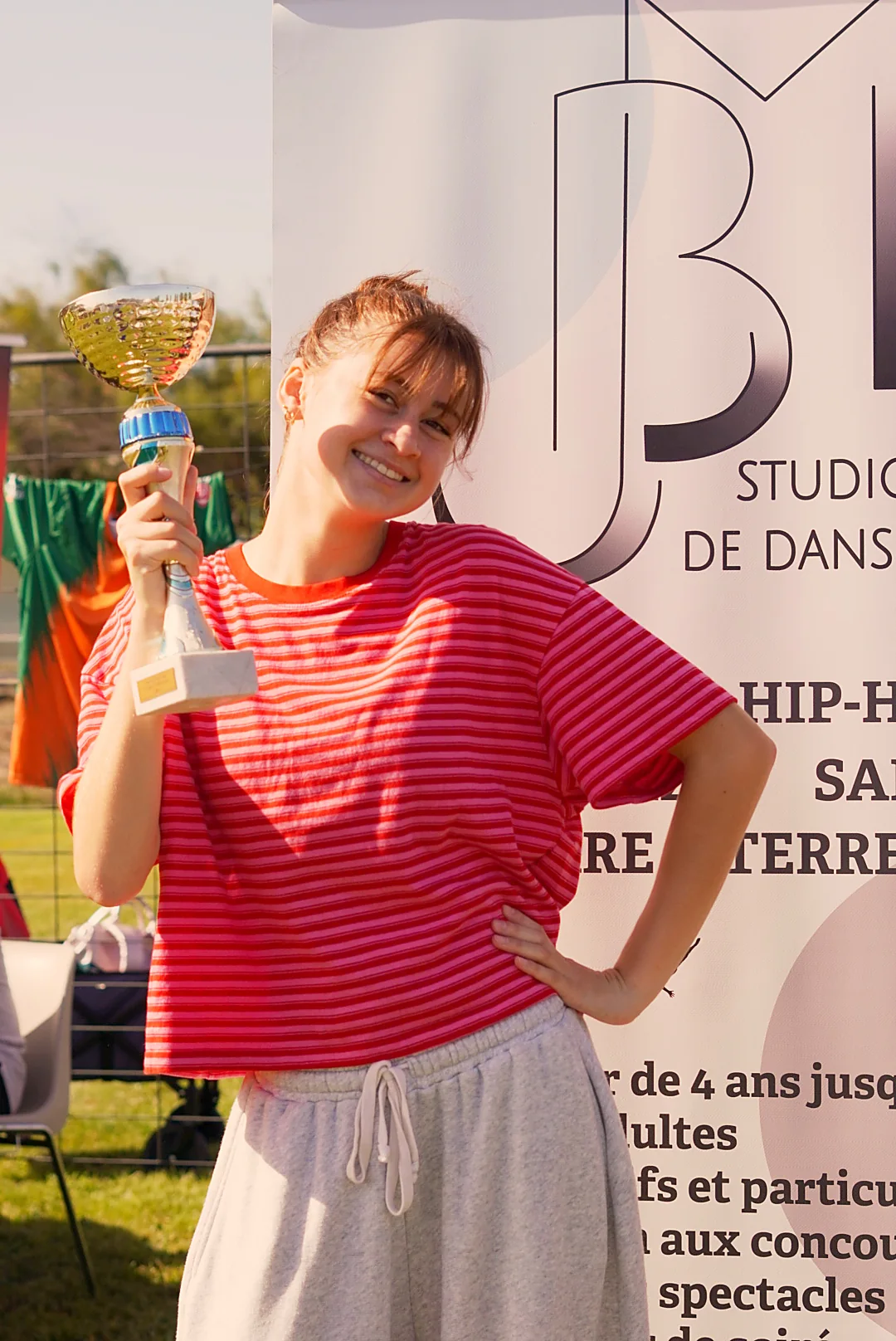 Une participante en haut rayé rouge sourit avec un trophée au forum des associations.