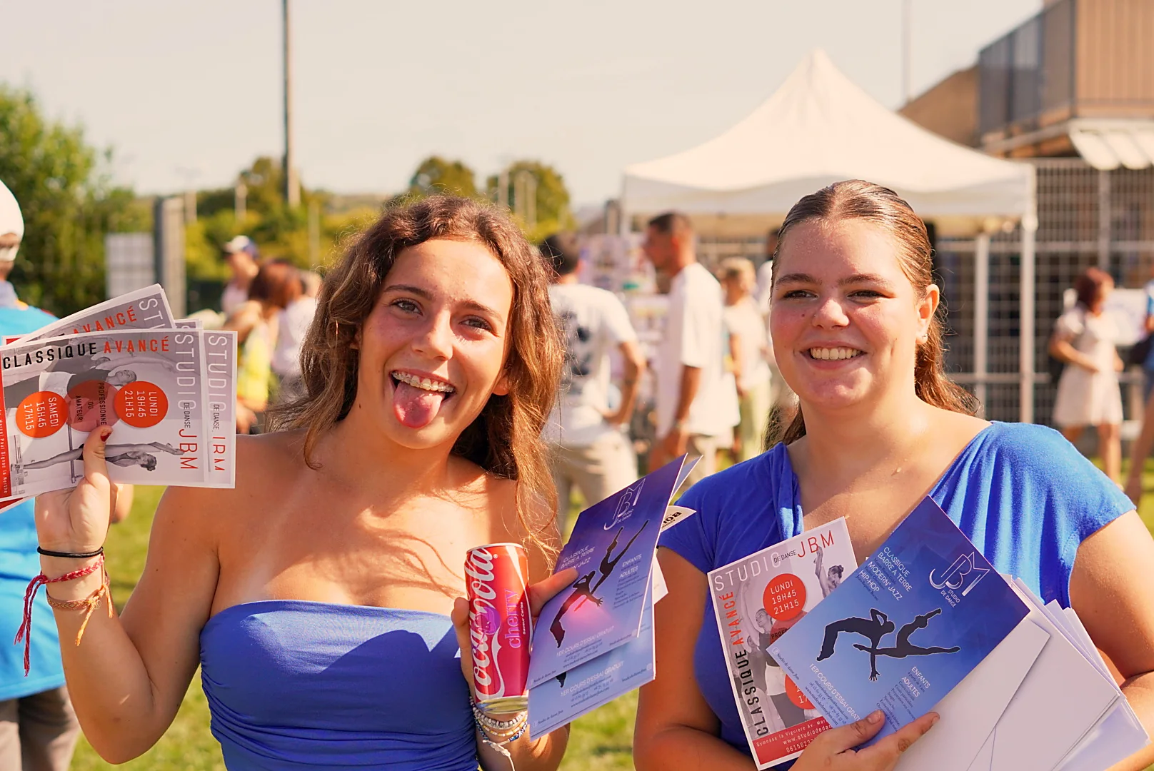 Deux participantes sourient et présentent des documents au forum des associations.