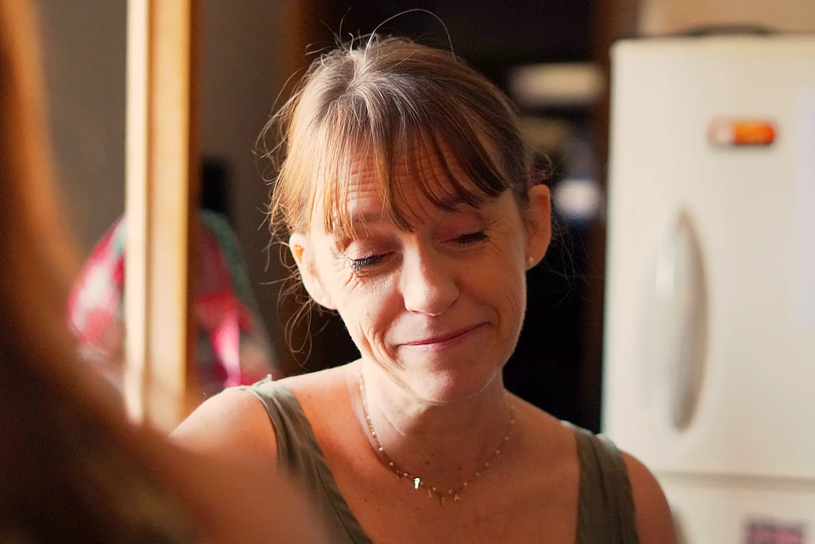 Une femme sourit doucement, les yeux baissés, à la crémaillère de Leslie.