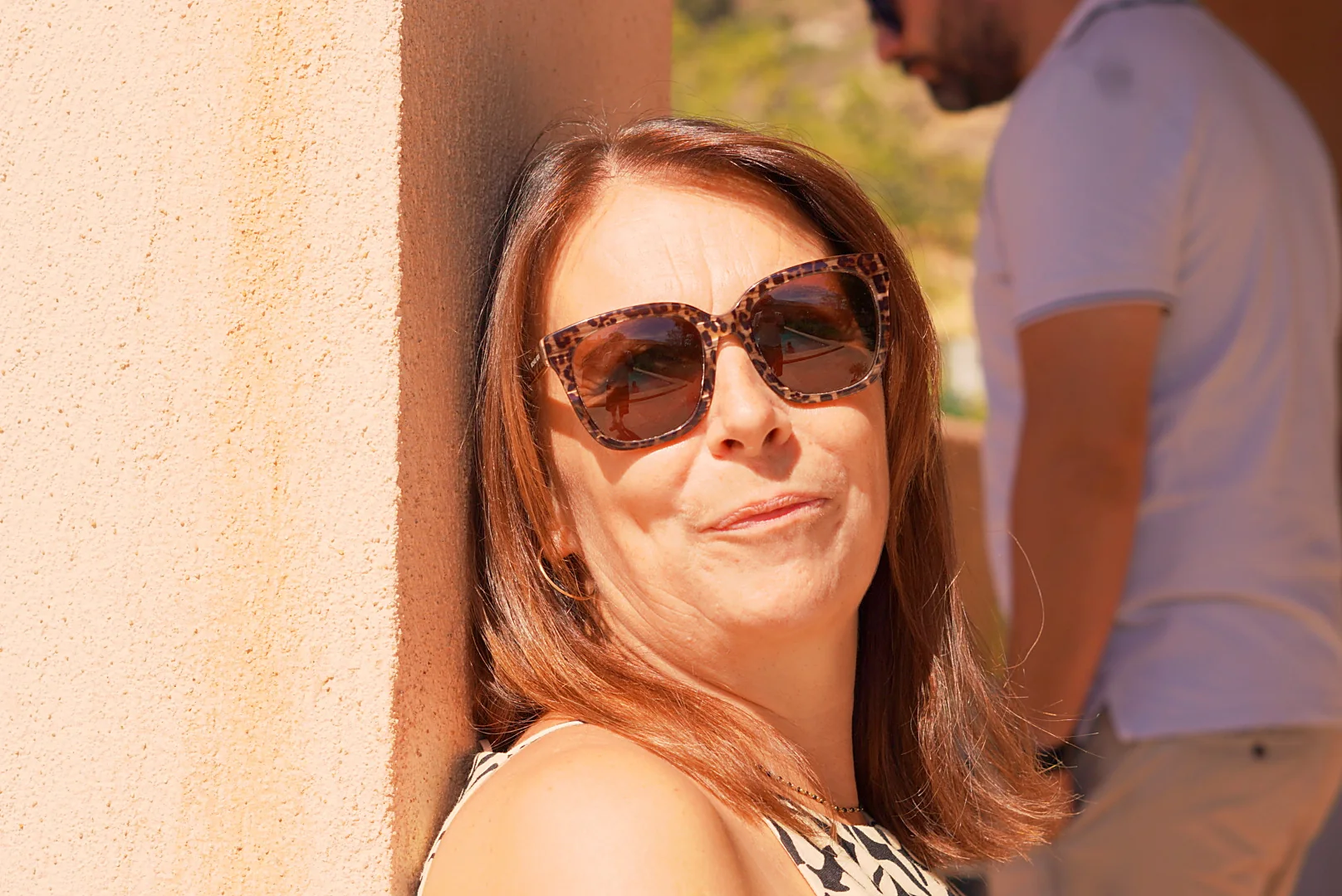Une femme portant des lunettes de soleil est photographiée près d’un mur ensoleillé à la crémaillère de Leslie.